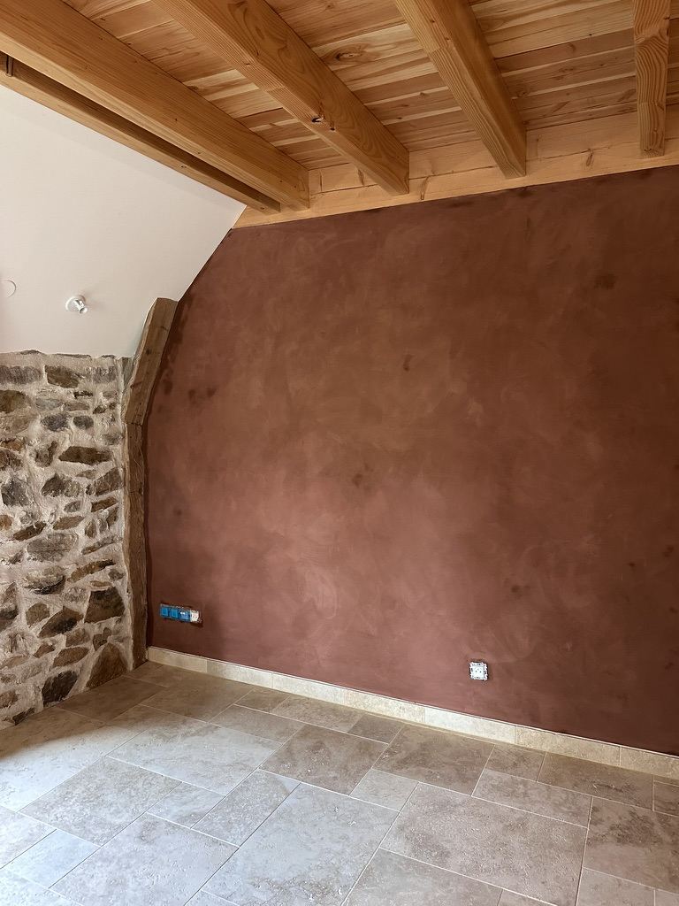 Mur en enduit mince à la chaux patiné terracotta, avec un buffet ancien en bois